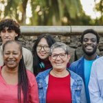 Multiracial people with different ages smiling on camera at city park - Community, inclusion and multiracial friends concept