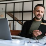 Confident young businessman reading book